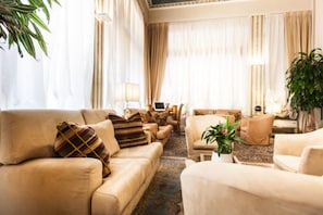 A spacious living room with beige sofas, a coffee table, and a potted plant. - Hotel San Luca (Verona)