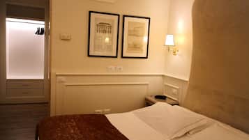 A hotel room with a bed, a nightstand, a lamp, and two framed pictures on the wall.