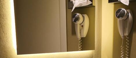 A bathroom with a white sink, a mirror, a hairdryer, and a towel rack.