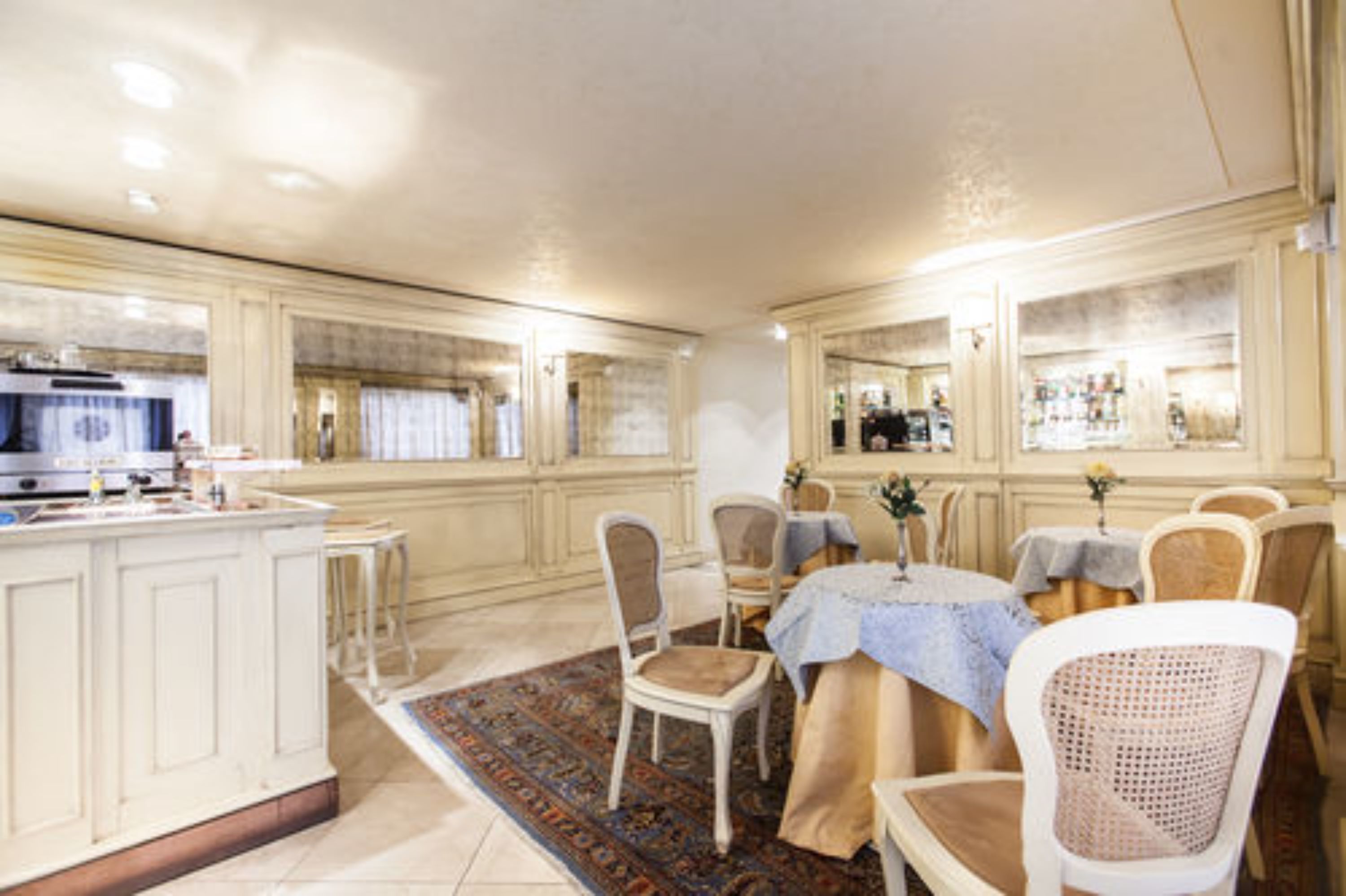 Une cuisine spacieuse dotée d’un grand îlot central, d’un coin bar et d’un espace repas avec chaises et tables.