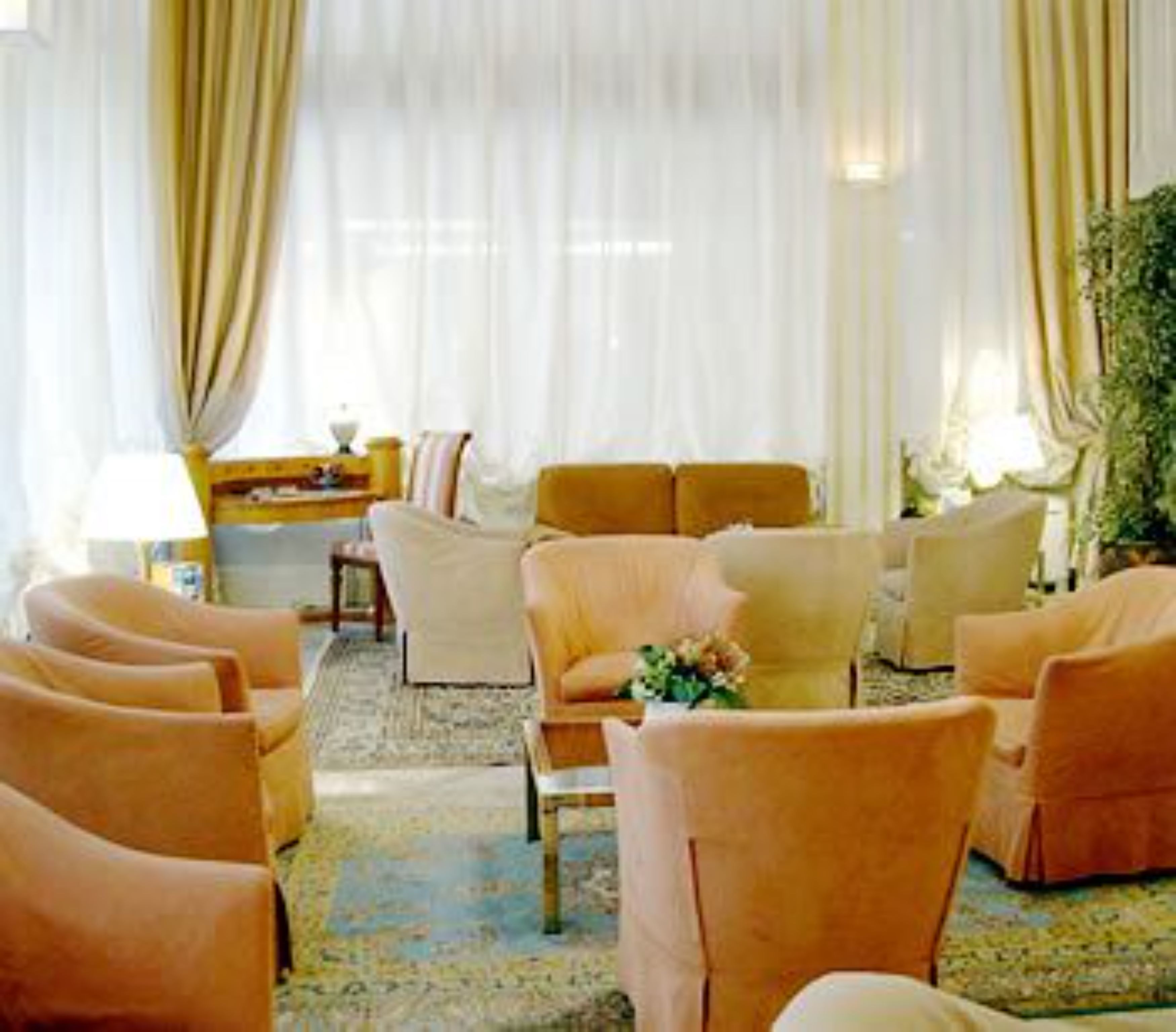 A room with a large window, a sofa set, and a small table with a lamp.