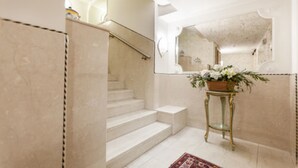 A staircase leading to a landing with a mirror and a small table with a floral arrangement. - Hotel San Luca (Verona)