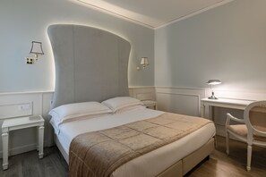 A neatly arranged bedroom with a large bed, bedside tables, a desk, and a chair.