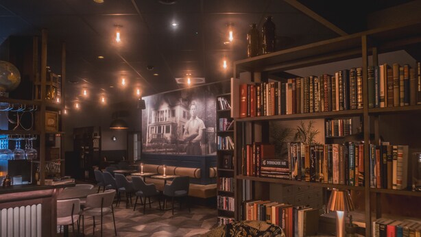 Una biblioteca acogedora con estanterías, un cartel grande y una zona de bar con asientos.