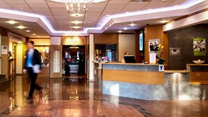 Un vestíbulo de hotel con una recepción, una araña y un piso pulido.