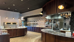 Una cocina moderna con armarios de madera, encimera de mármol e iluminación colgante.