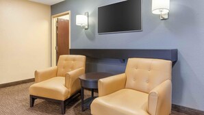 A room with two leather armchairs, a small round table, a flat-screen TV mounted on the wall, and two wall-mounted lamps. - Extended Stay America Select Suites - Appleton - Fox Cities (Appleton)