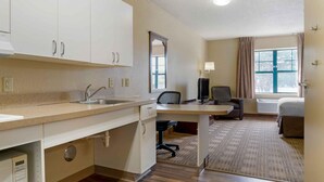 A hotel room with a kitchenette, a desk, a chair, a bed, and a window with curtains. - Extended Stay America Select Suites - Appleton - Fox Cities (Appleton)