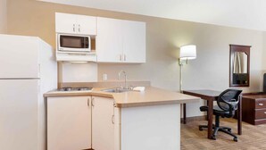 A compact kitchen with a microwave, sink, and a small dining area with a chair. - Extended Stay America Select Suites - Appleton - Fox Cities (Appleton)