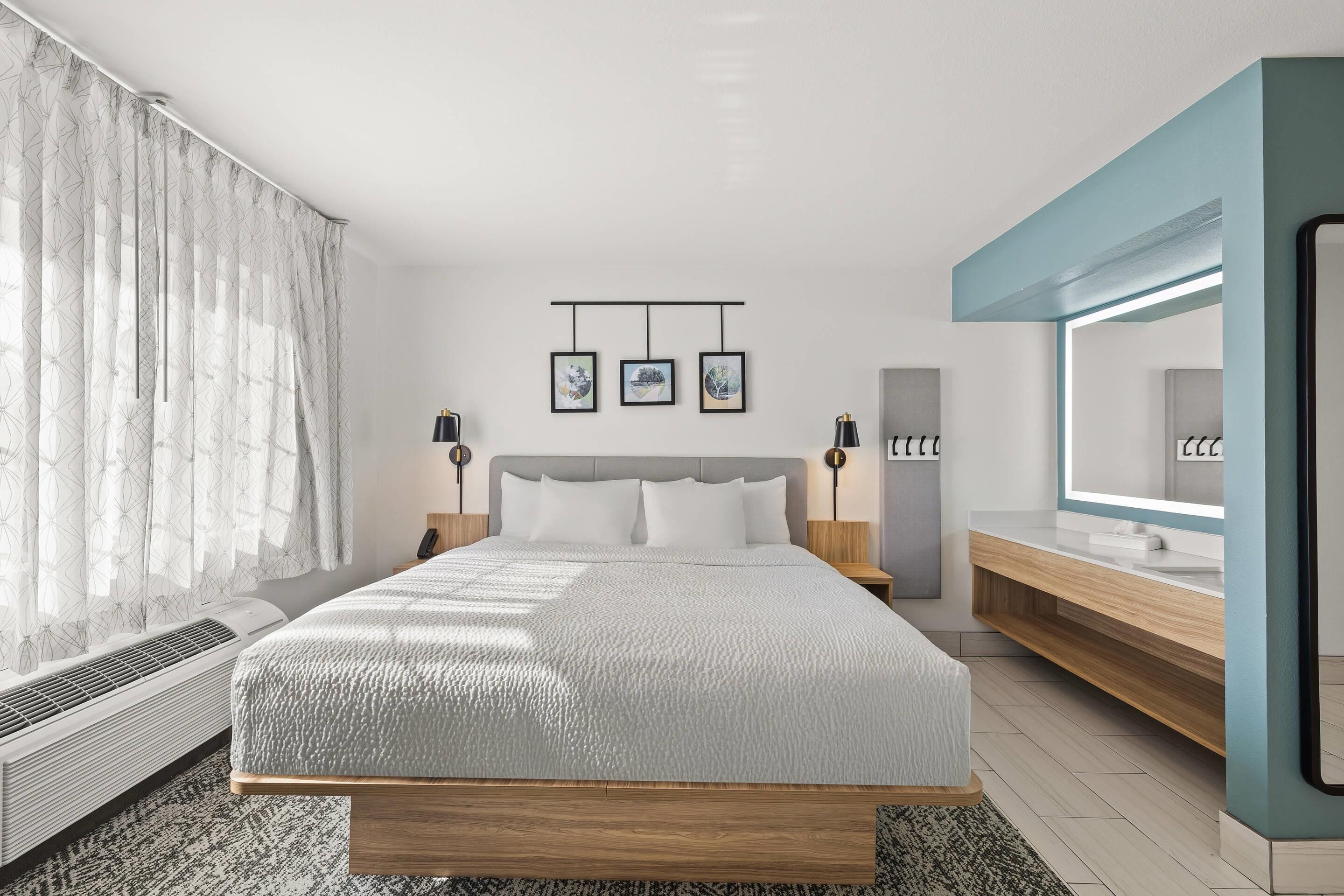 Un dormitorio moderno con una cama grande, mesitas de noche con lámparas, un armario empotrado y un espejo amplio.