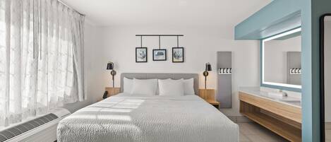 A modern bedroom with a large bed, bedside tables with lamps, a built-in wardrobe, and a large mirror.