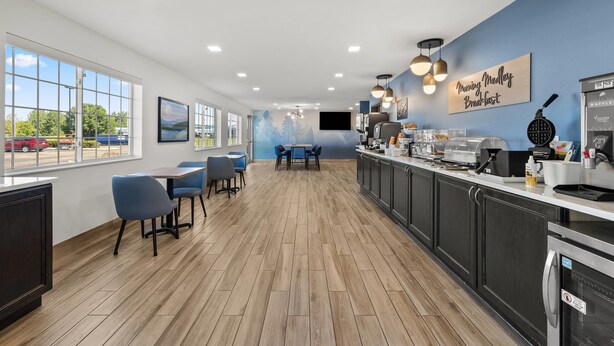 Una cocina moderna con barra americana, piso de madera y vista al estacionamiento.