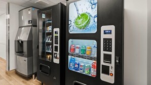 Máquina expendedora con un gráfico de rodaja de limón, una pantalla digital y diversas opciones de bebidas, incluyendo Coca-Cola, Sprite y Pepsi.