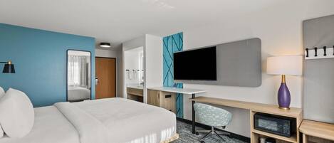 Una habitación de hotel moderna con una cama grande, un escritorio, un televisor y una silla.