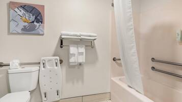 Un baño con inodoro, ducha con cortina, toallero con toallas y dispensador de papel higiénico en la pared.