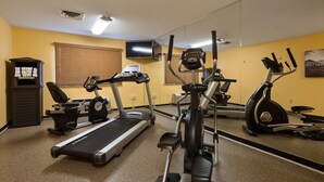 Un gimnasio con cintas de correr, elípticas y una bicicleta estática.