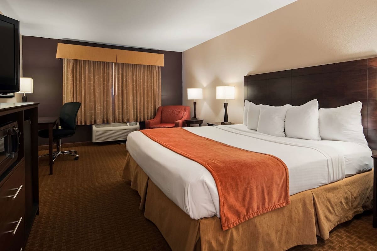 A hotel room with a large bed, a television, a desk, and a chair.
