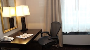 A hotel room with a desk, two lamps, a chair, a telephone, and a window with curtains. - Holiday Inn Budd Lake - Rockaway Area by IHG (Budd Lake)