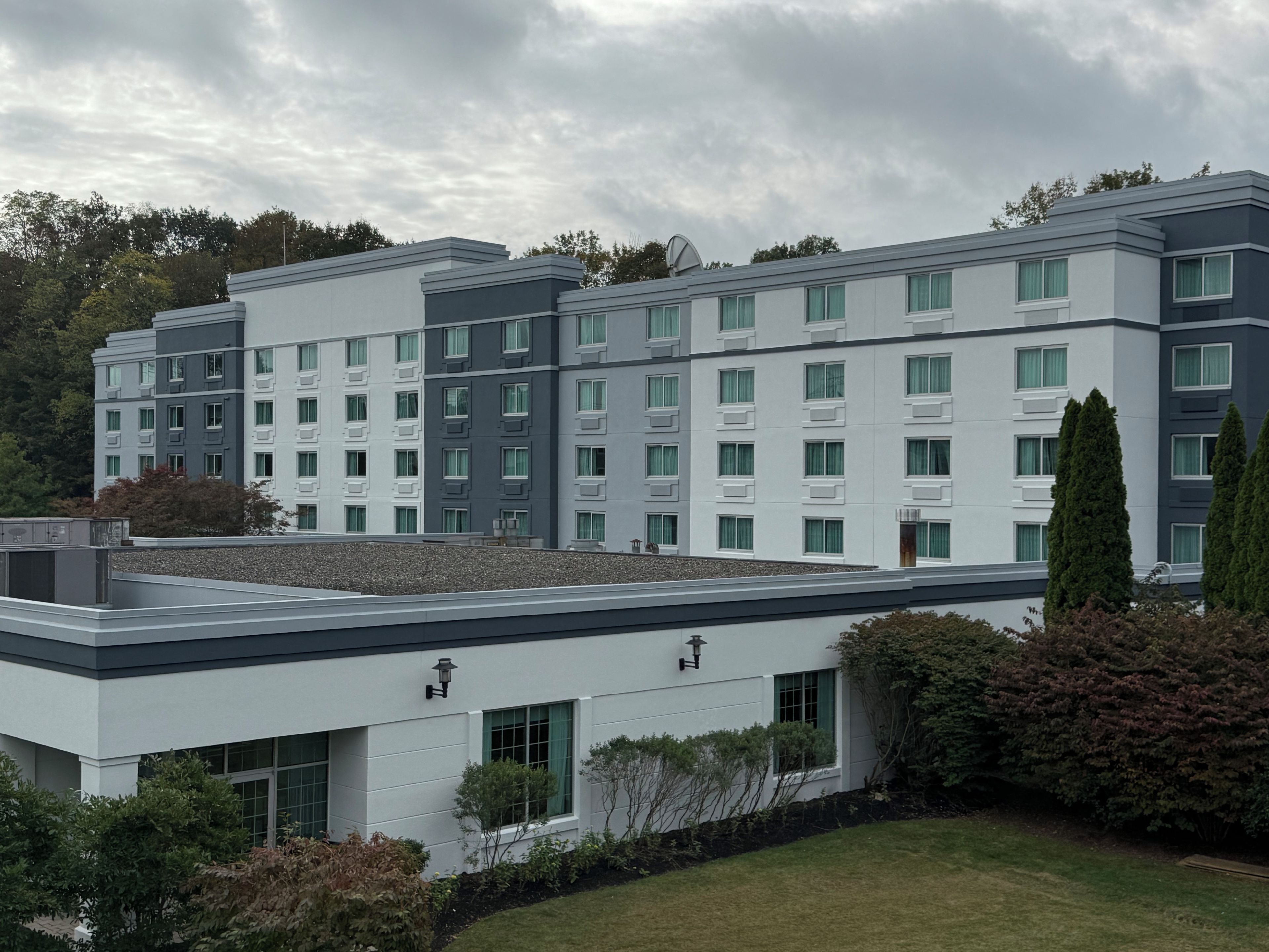 Un hotel de varios pisos con un diseño arquitectónico moderno, que incluye un techo plano y una combinación de estilos de ventanas.