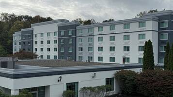 Un hotel de varios pisos con un diseño arquitectónico moderno, que incluye un techo plano y una combinación de estilos de ventanas.