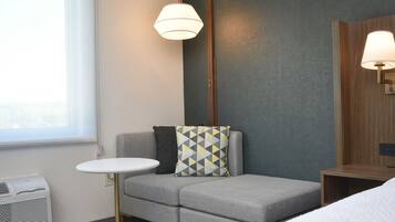 A hotel room with a grey sofa, a small round table, and a bed.