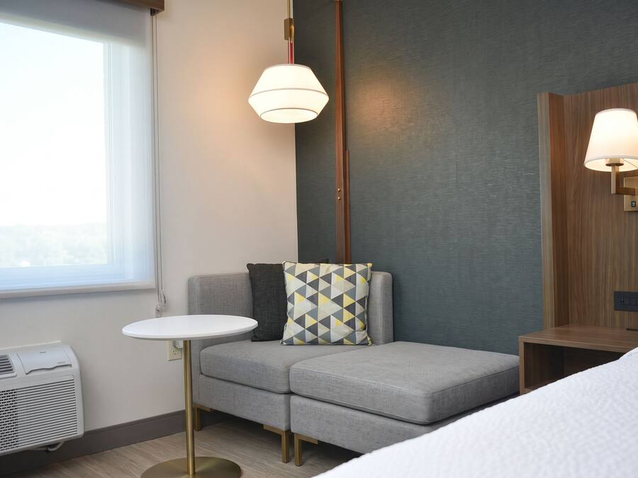 A hotel room with a grey sofa, a small round table, and a bed.