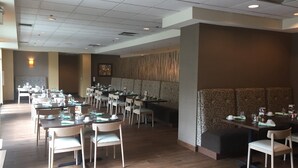 A spacious restaurant with multiple tables and chairs, a patterned wall, and a ceiling with recessed lighting. - Holiday Inn Budd Lake - Rockaway Area by IHG (Budd Lake)