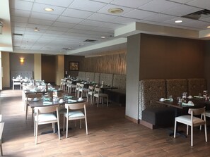 A spacious restaurant with multiple tables and chairs, a patterned wall, and a ceiling with recessed lighting. - Holiday Inn Budd Lake - Rockaway Area by IHG (Budd Lake)