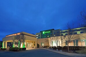 A Holiday Inn hotel with a modern design, featuring a well-lit entrance and a parking area. - Holiday Inn Budd Lake - Rockaway Area by IHG (Budd Lake)