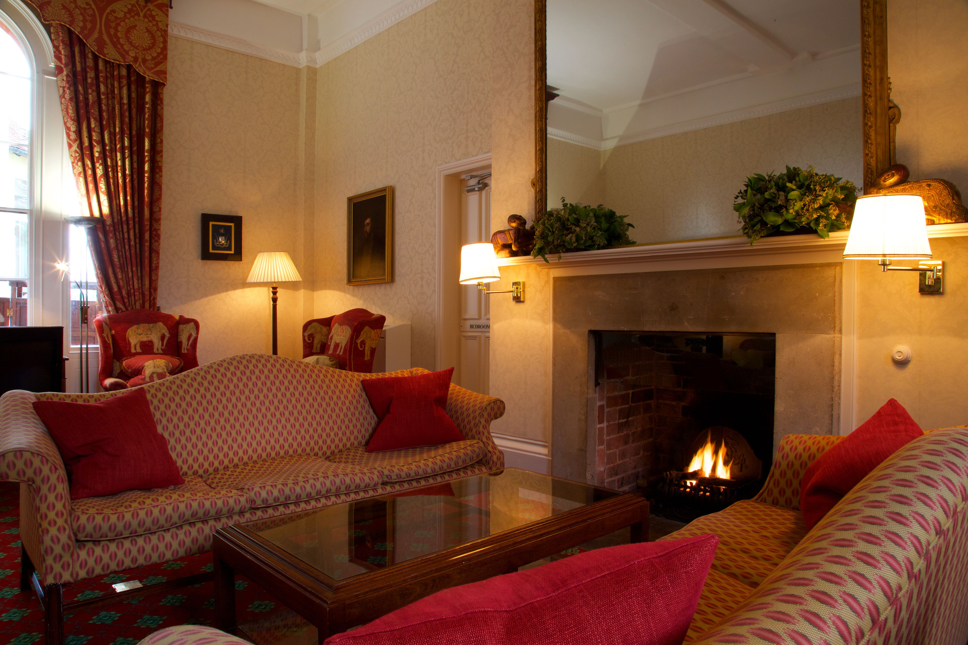 A cozy living room with a fireplace, patterned sofas, and a glass coffee table.