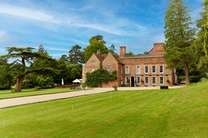 A large brick building with a symmetrical facade, multiple windows, and a well-maintained lawn. - Flitwick Manor (Bedford)