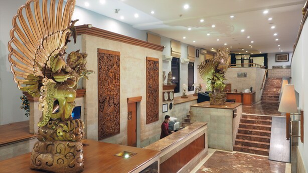 A hotel lobby with a reception desk, a staircase, and a clock. - Jakarta Airport Hotel (Tangerang)