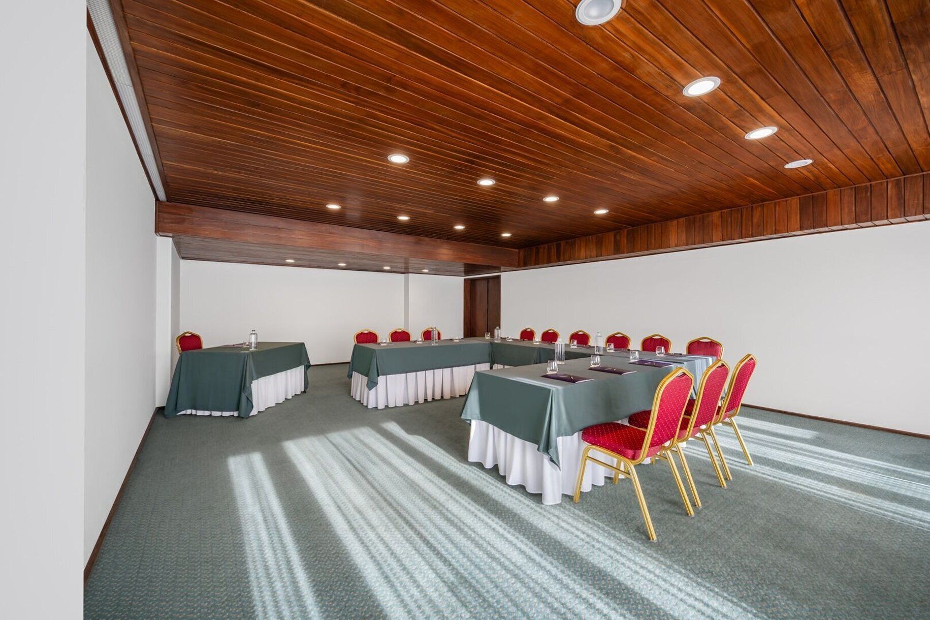 Une salle de conférence équipée de tables, de chaises et dotée d’un plafond en bois.