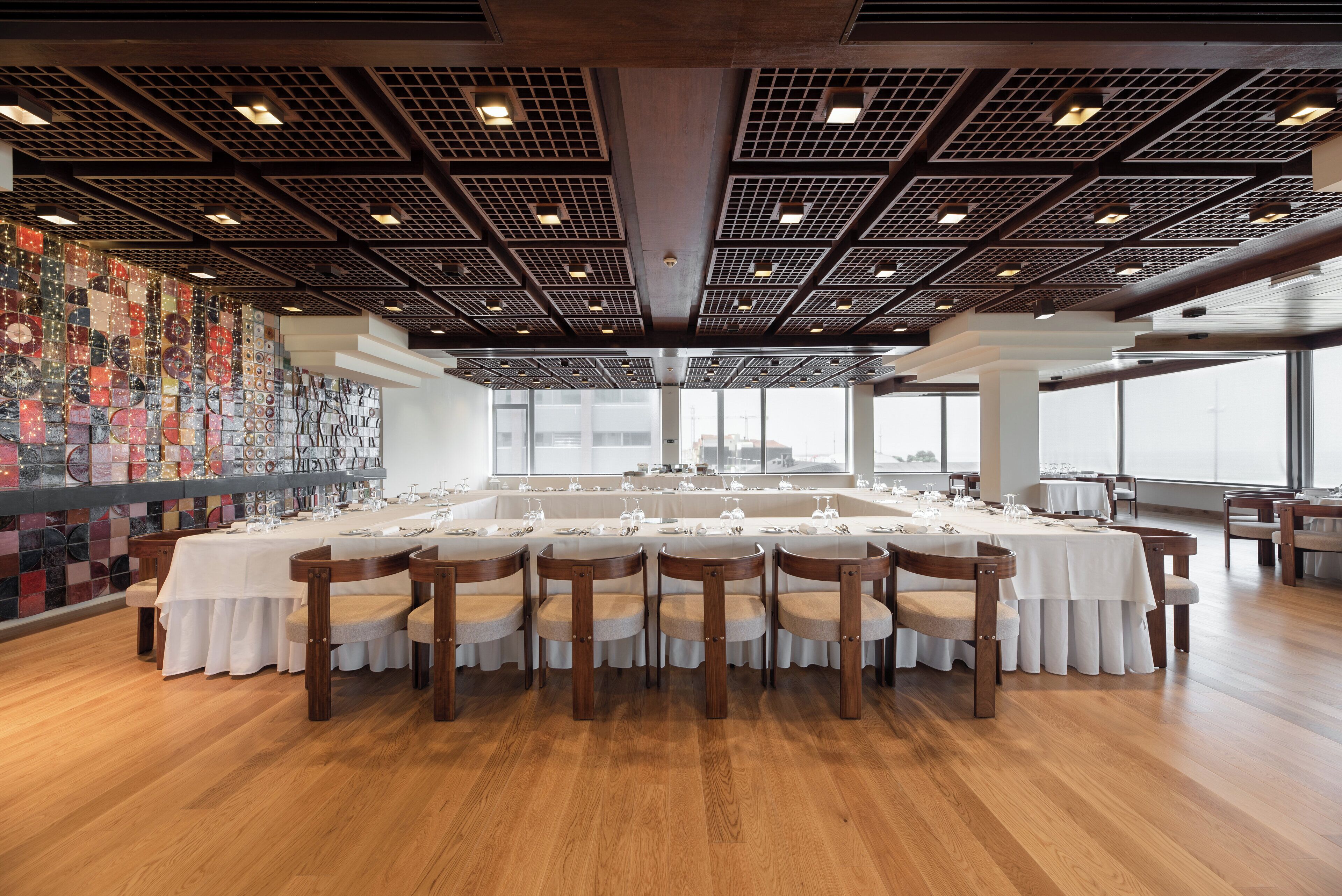 A large dining area with long tables, chairs, and a decorative wall.