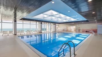 Una piscina cubierta, sombrillas, tumbonas