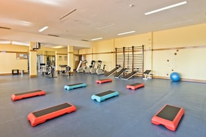 Een sportschool met diverse fitnessapparatuur en stepbokken.
