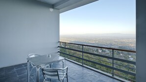 A balcony with a table and chairs, offering a view of a cityscape and a body of water. - Lam Hotel Caramulo  (Tondela)