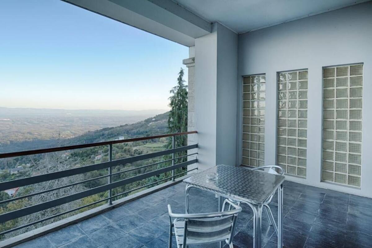 A balcony with a table and chairs, a railing, and a view of a landscape.
