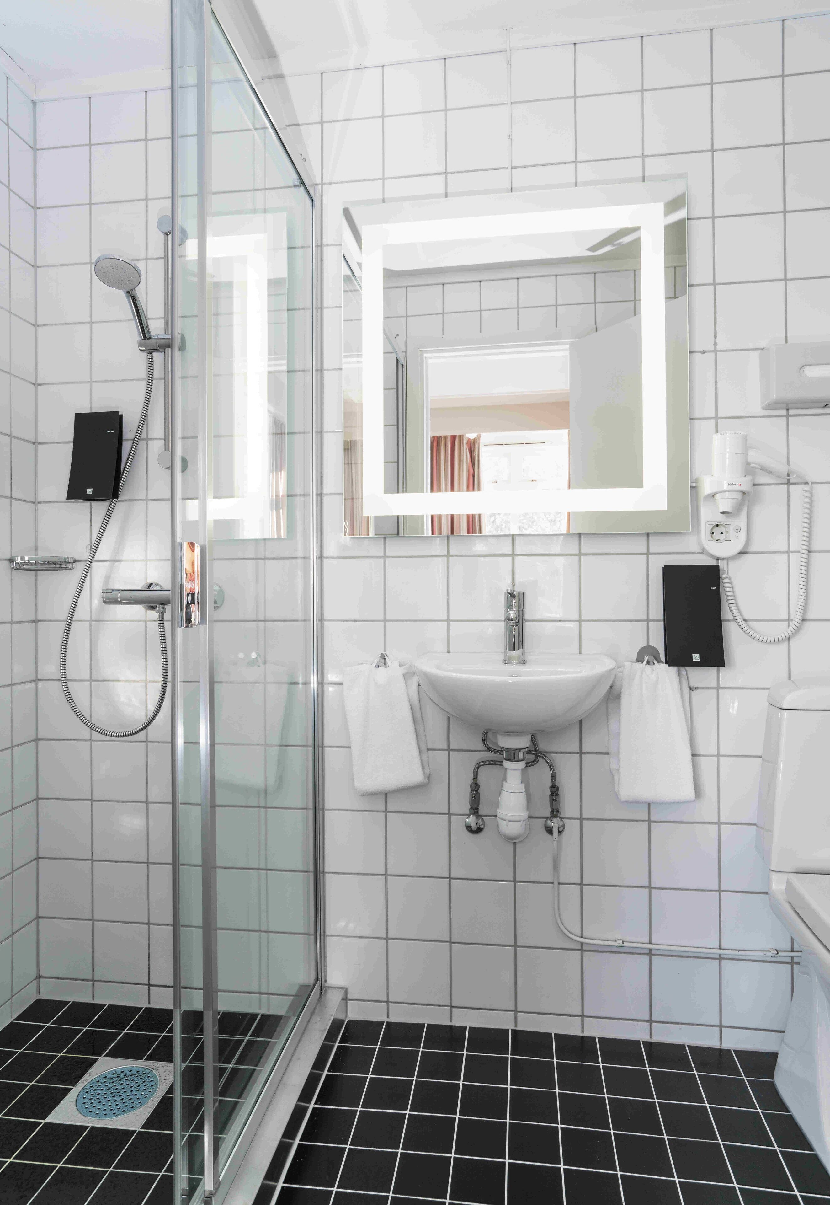 Une salle de bain moderne avec une douche à parois de verre, un lavabo avec un miroir au-dessus et des toilettes.
