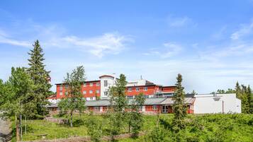 Un edificio a più piani con facciata rossa e bianca, circondato da vegetazione e alberi.