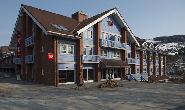 A hotel with a brick facade, multiple balconies, and a clear view of a snowy landscape in the background.