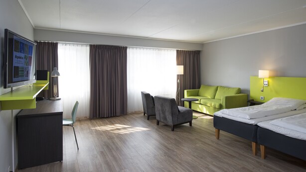 A hotel room with a bed, a desk with a computer, a chair, a sofa, and a TV. - Thon Hotel Hallingdal (Al)