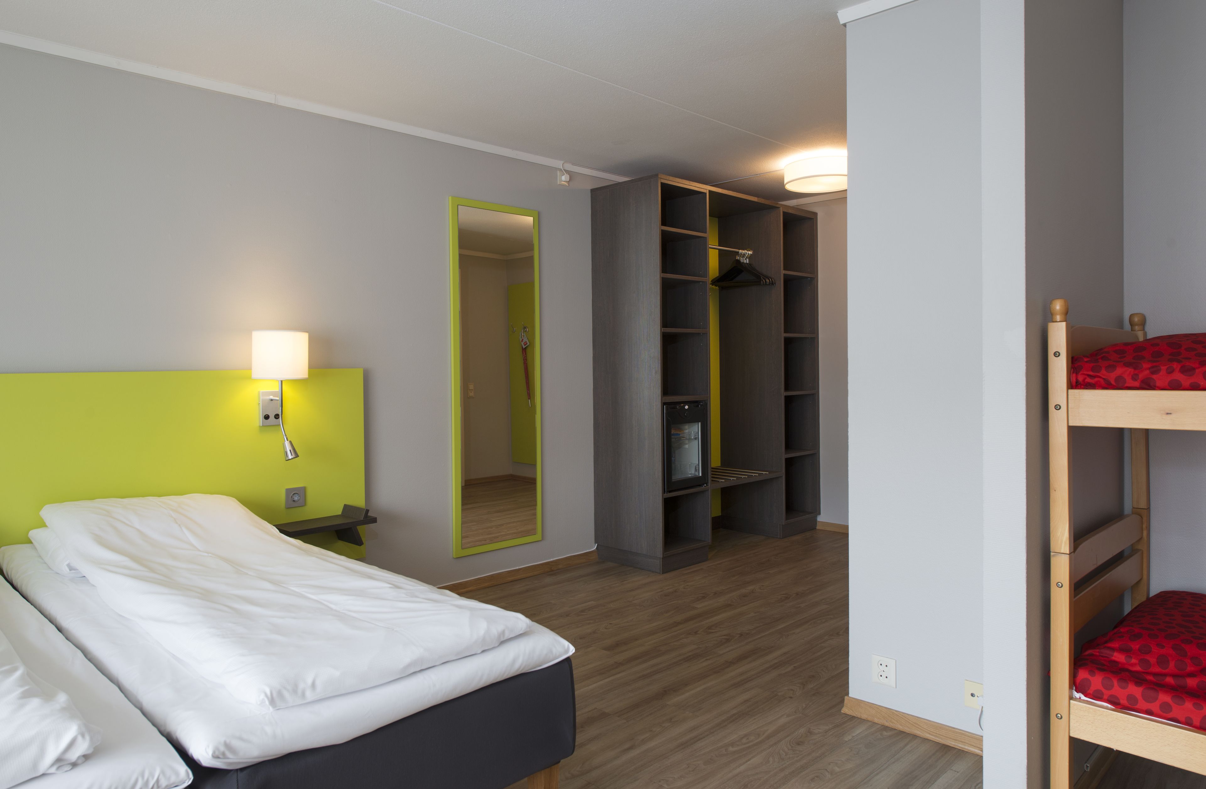 Une chambre d’hôtel avec un lit, une armoire et un miroir.