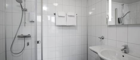 Un baño moderno con cabina de ducha de vidrio, un lavabo blanco y un espejo.