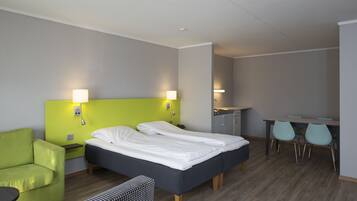 Una habitación de hotel con cama, escritorio, silla y sofá.