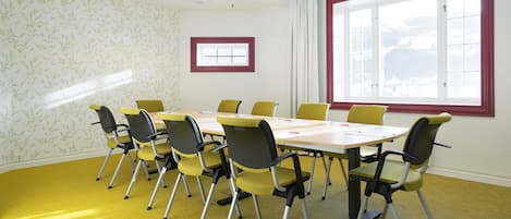 Un salón de conferencias con una gran mesa, sillas amarillas y una ventana con vistas a un paisaje nevado.