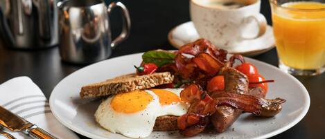 Un plato de desayuno con huevos, tocino, tomates y tostadas.