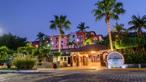 Un hotel con una fachada colorida, palmeras y un letrero que dice 'Decameron Los Cocos'.