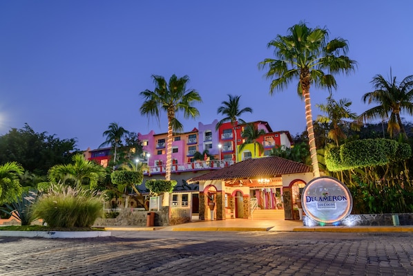 Un hotel con una fachada colorida, palmeras y un letrero que dice 'Decameron Los Cocos'.