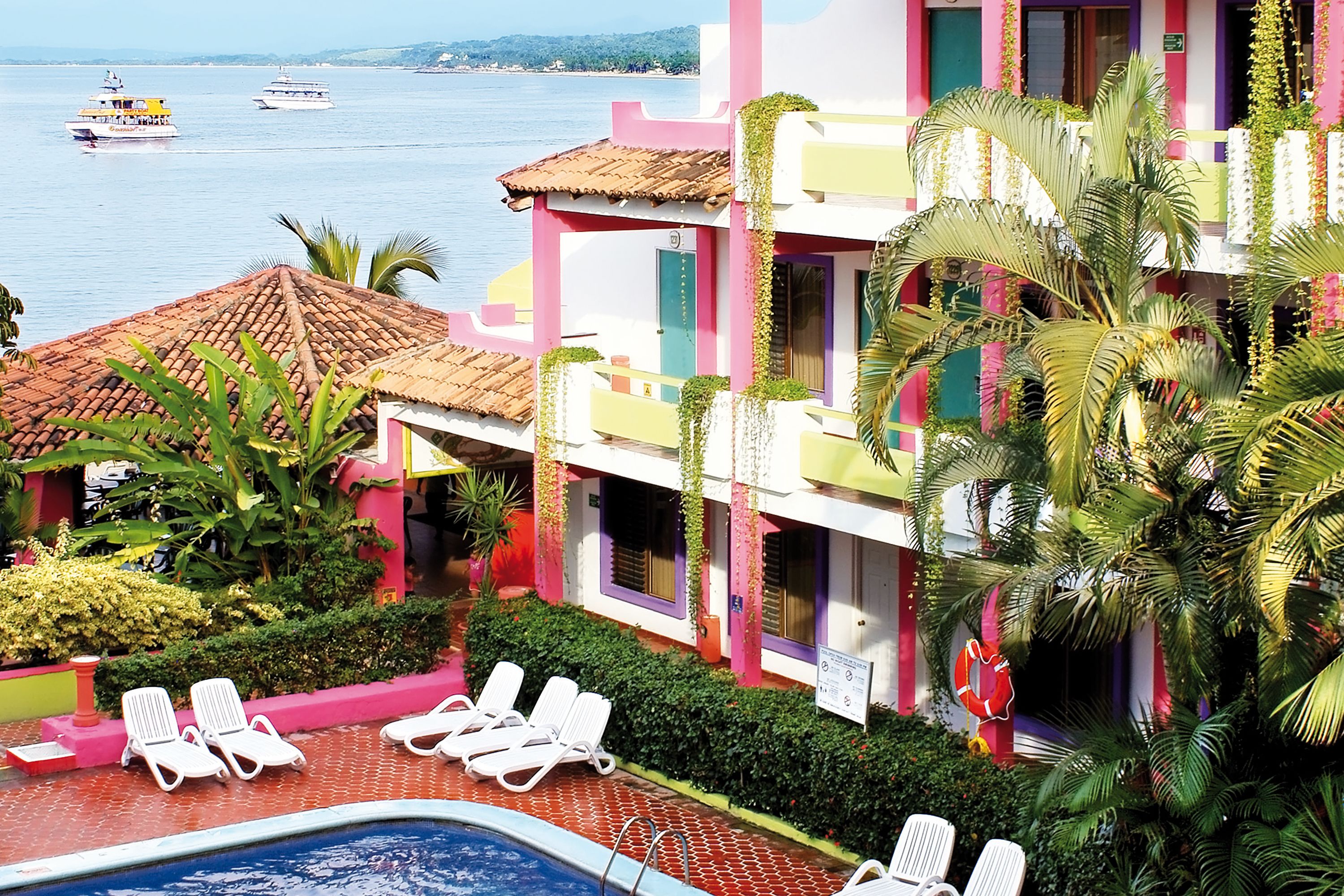Un hotel con piscina, sillones de descanso y vistas al mar.